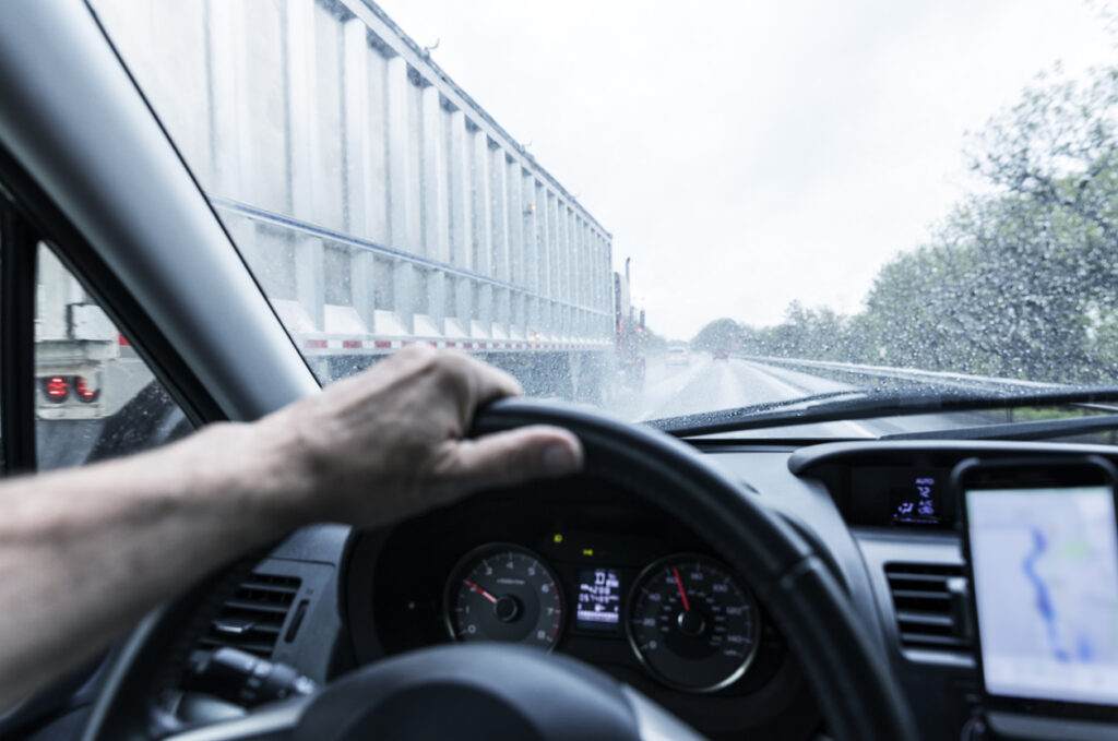 person-driving-car-speeding-past-semi-truck