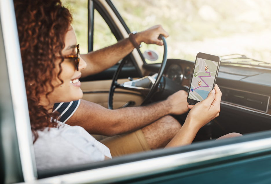 passenger woman reading map on cell phone during summer road trip