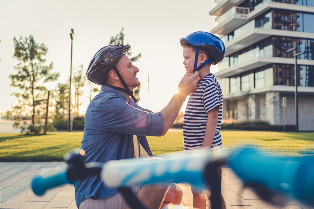 man-helping-child-buckle-bicycle-helmet
