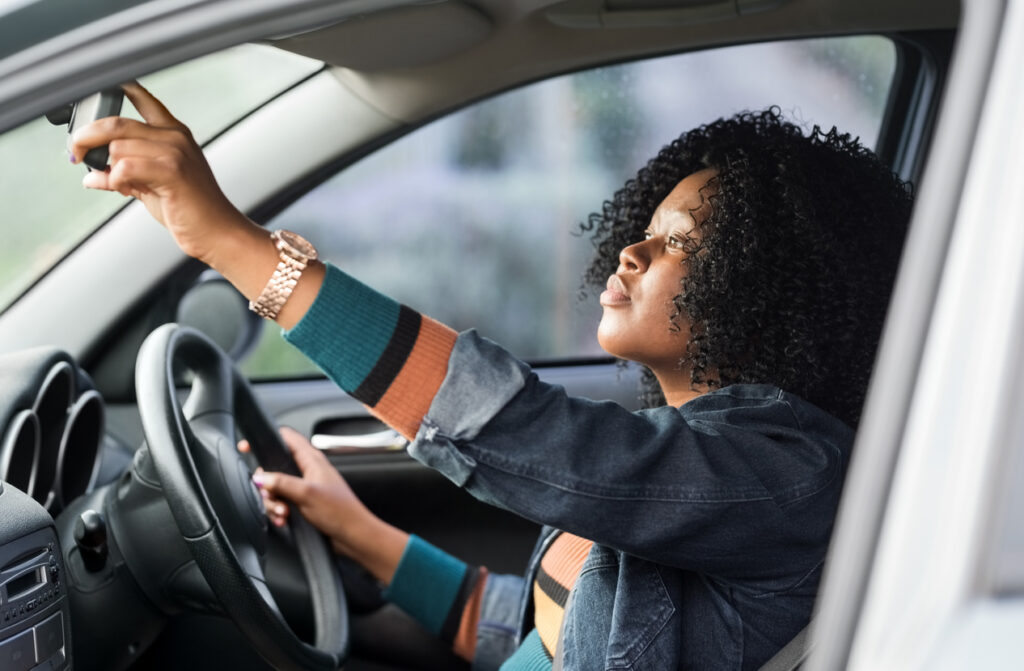 woman-adjusting-rear-view-mirror-of-vehicle