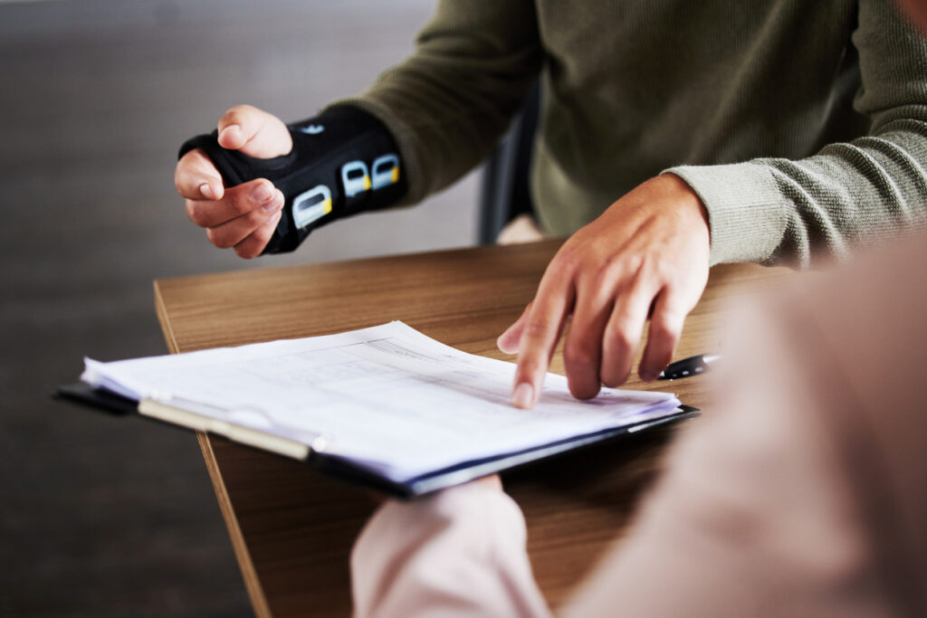 man with broken wrist signing papers to get compensation for personal injury